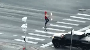 Fire-juggling unicyclist caught on camera blocking traffic in major roadway as police intervene